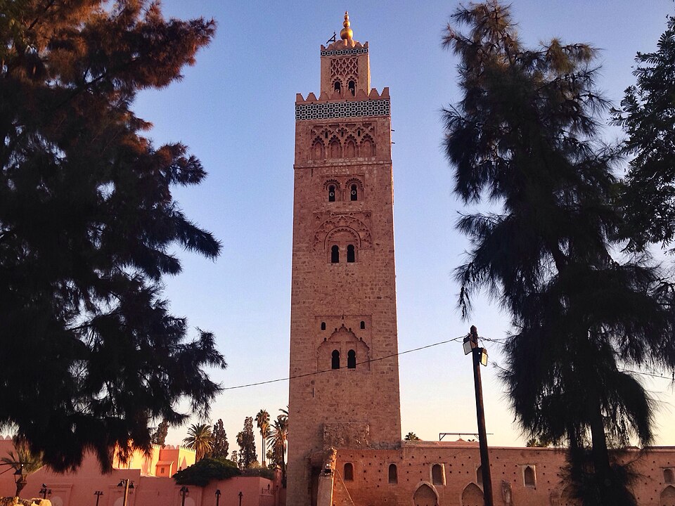 The minaret of the Koutoubia Mosque in Marrakesh at dusk, framed by two trees